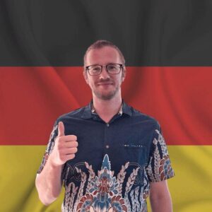 Niko, the founder of How to Study German, standing in front of a German flag.