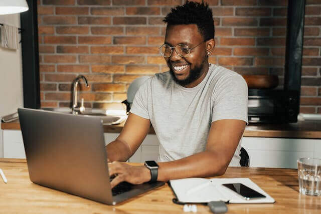 A cheerful student practicing the German verb 'sein' through online grammar exercises at home.