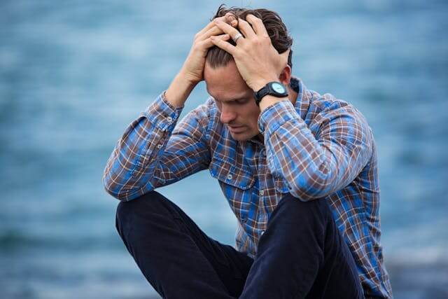 A distressed man holding his head, representing German language stress vocabulary such as Sorgen (worries).