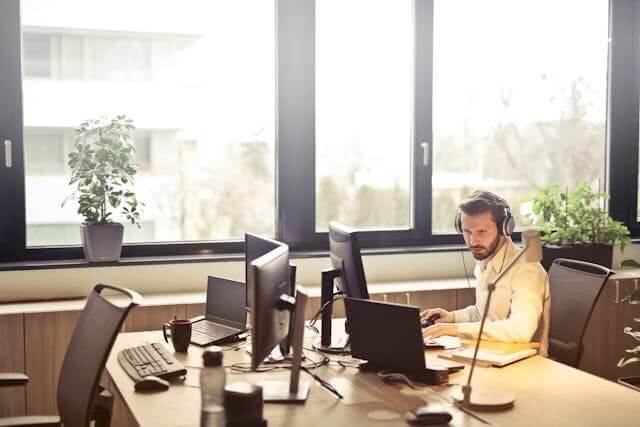 A man wearing headphones at a computer desk symbolising the German Office Vocabulary Quiz.