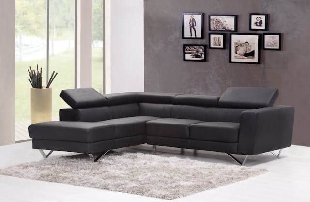 A modern black sectional sofa near a glass window, symbolising comfort and style for a German Short Story on Home and Living Vocabulary.