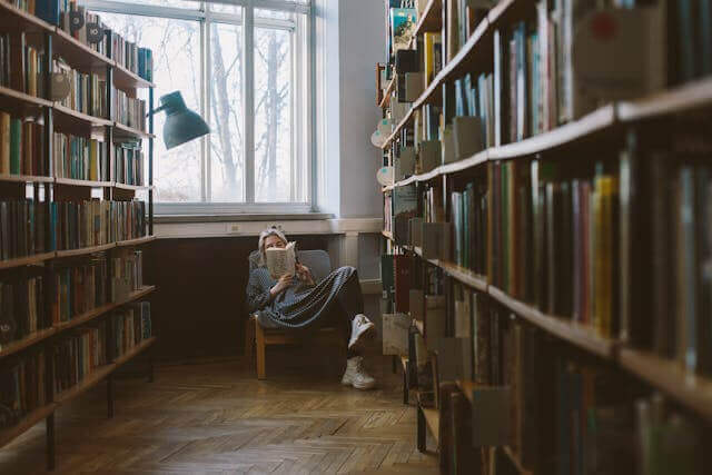 A person reading a book in a cozy library corner, perfect for exploring German literature and books vocabulary.