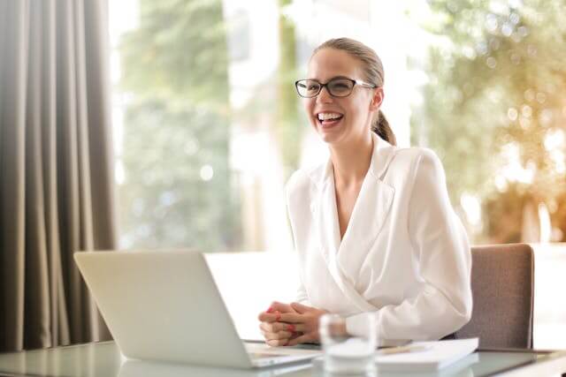 A professional woman smiling at her desk, learning German Accusative Prepositions.