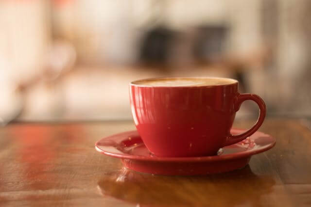 A red coffee cup on a wooden table, symbolising A German Short Story featuring Daily Routine Vocabulary.