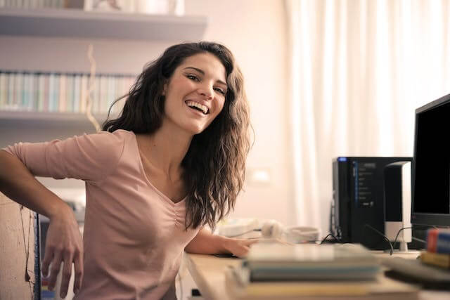 A smiling woman at a desk symbolising progress with the German Concessive Clauses Quiz Obwohl vs. Trotzdem.