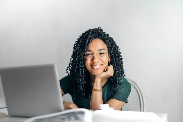 A smiling woman with a laptop, symbolizing focus on the German Present Tense Quiz.