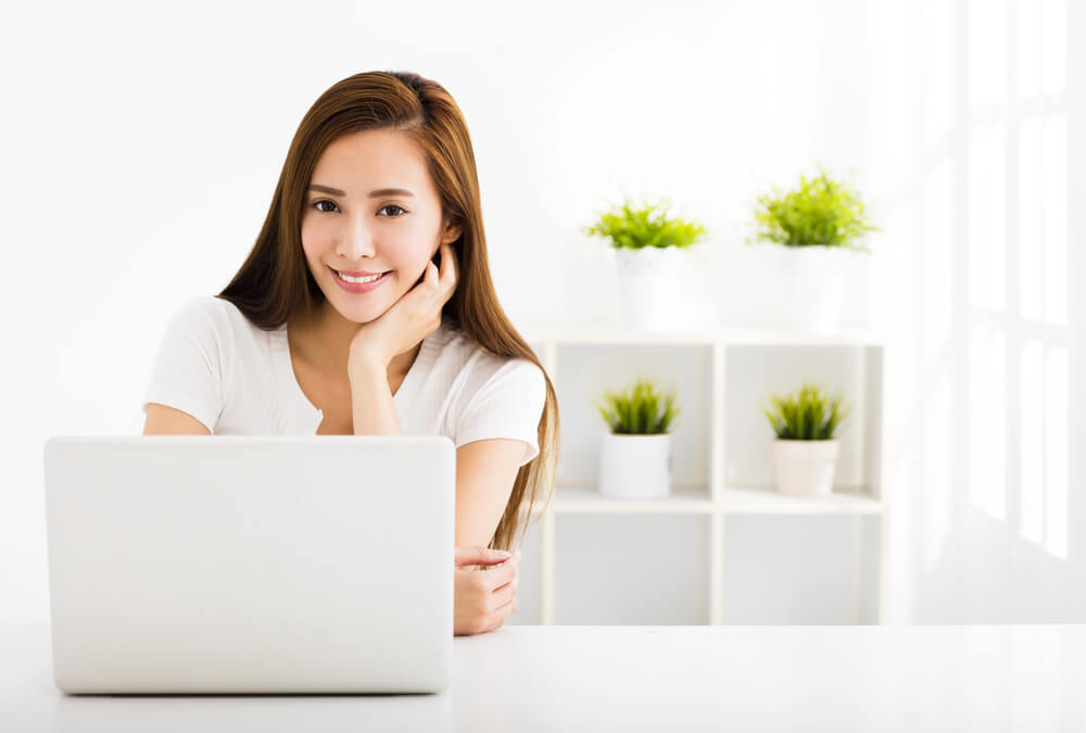 A smiling woman working on her laptop, symbolising preparation for the German Final Clauses Grammar Quiz.