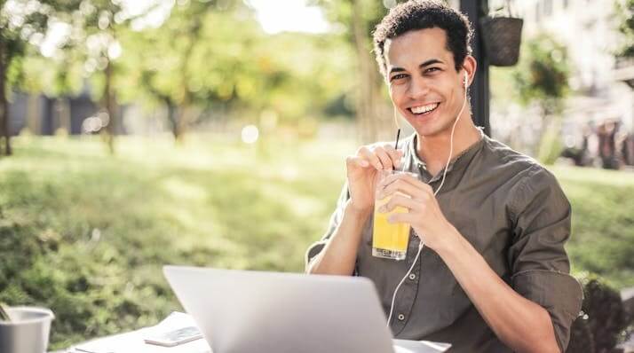 A smiling young man working outdoors with a drink, symbolizing focus on the German Grammar Quiz Dative or Accusative.