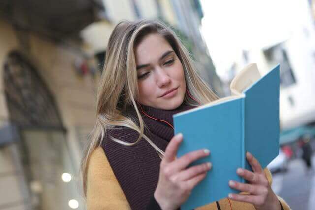 A student reading a book outdoors to master the German Simple Past Tense for better communication skills.