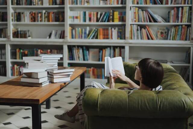 A woman reading a book in a library symbolising a love for German literature for the German Literature and Books Vocabulary Quiz.