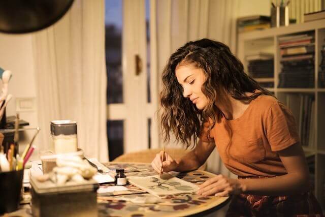 A young woman painting on paper symbolising the German Hobbies Vocabulary Quiz.