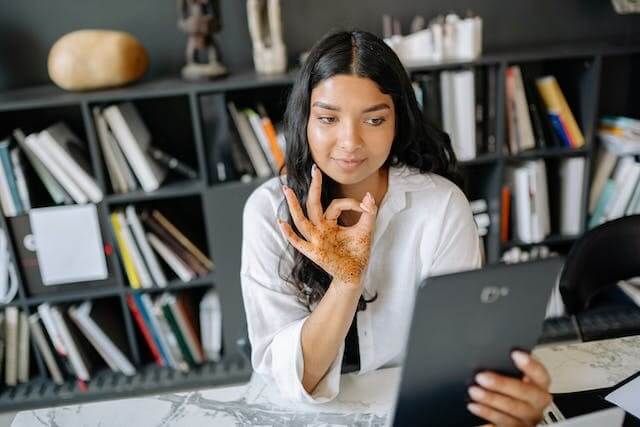 A young woman showing an OK gesture while looking at her tablet, symbolizing success in the German Dative Case Quiz.