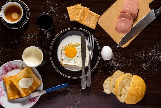 Breakfast table with bread, fried egg, coffee, and salami, illustrating German daily routine vocabulary like das Frühstück (breakfast).