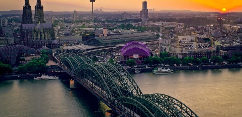 Cologne skyline at sunset with Hohenzollern Bridge and Cathedral, representing the beauty of learning German Final Clauses in context.