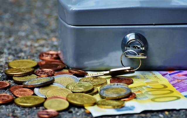 Euro banknotes and coins next to a locked safety box, representing A German Short Story featuring Banking Vocabulary.