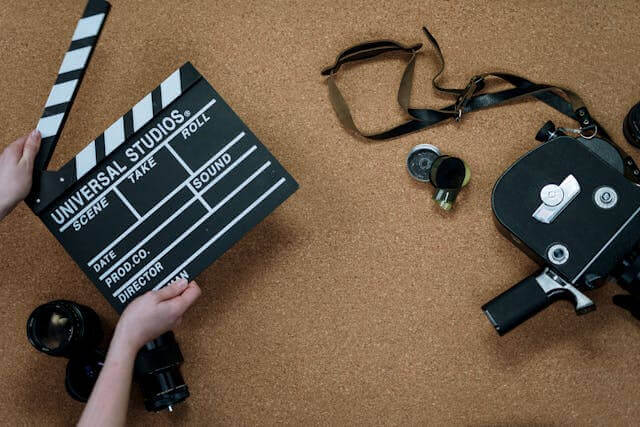 Film equipment, including a clapperboard and camera, illustrating key terms in German cinema vocabulary for filmmaking.