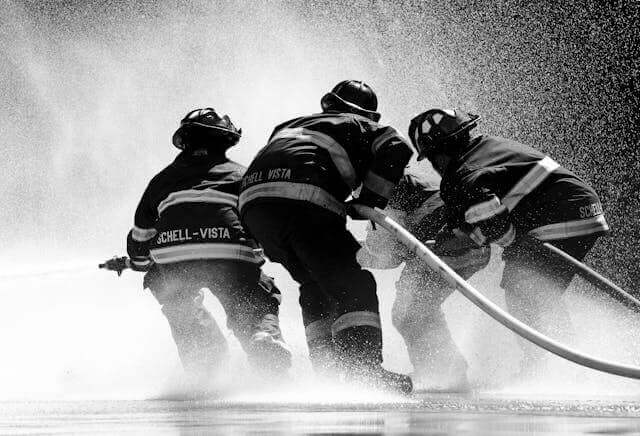 Firefighters in action with a hose, representing practical terms in German emergency vocabulary.