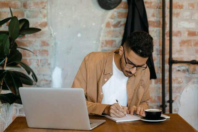 Focused man studying German N-Declension grammar at a café.