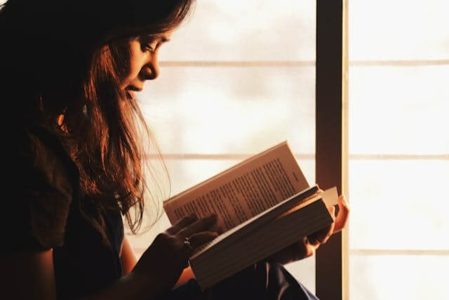 Focused woman reading a book about German cases and articles.