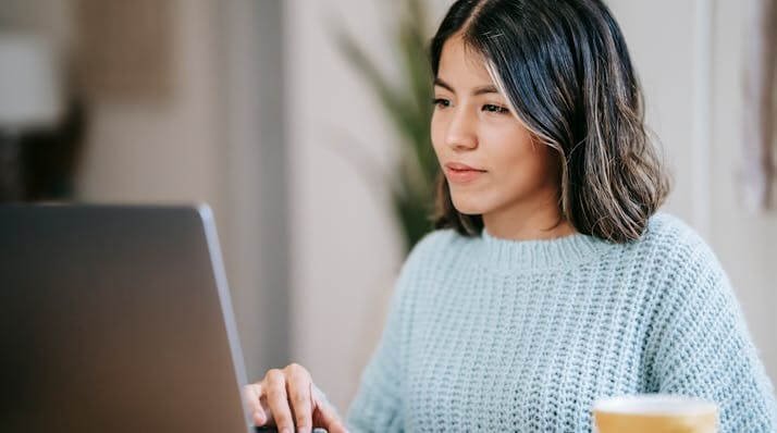 Focused woman studying for a German Simple Past Quiz on her laptop.