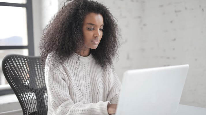 Focused woman using a laptop to show engagement with a German accusative case quiz.