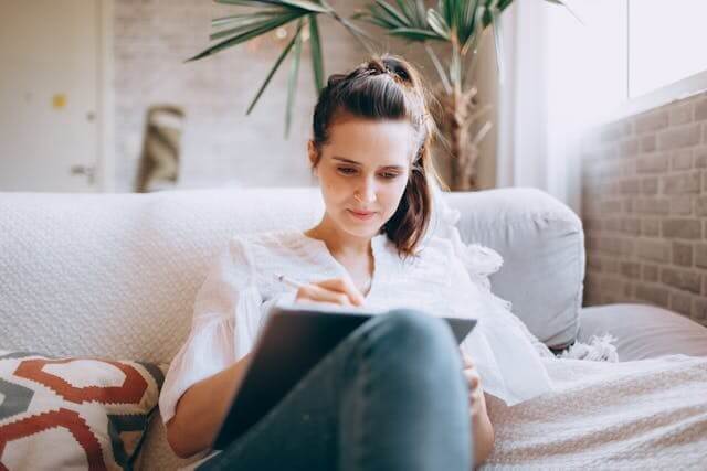 Focused woman writing on a tablet to show engagement with our German prepositions quiz.