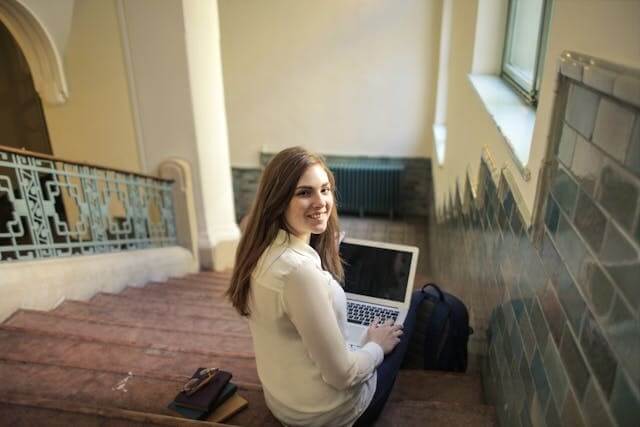 Woman sitting on stairs with a laptop symbolizing a German short story for beginners.