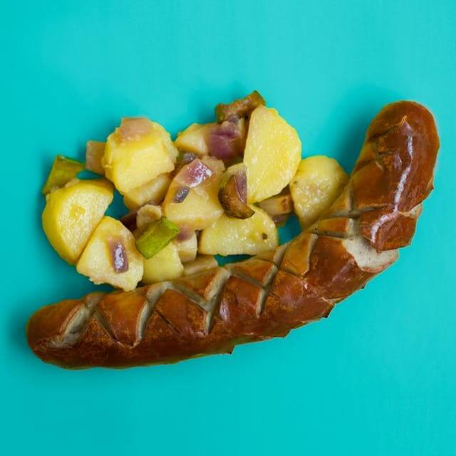 German sausage and potato salad on a vibrant turquoise background, symbolising A German Short Story featuring Food Vocabulary.