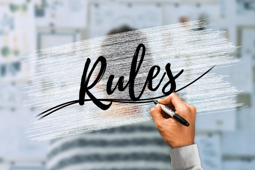 Handwriting the word 'Rules' on a transparent overlay, representing guidelines for understanding German Article Rules.