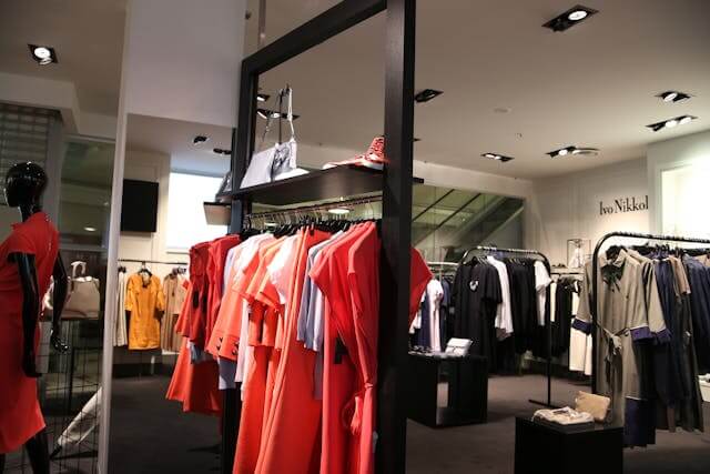 Modern clothing store with colorful garments, illustrating German clothing vocabulary like das Kleid (dress) and der Mantel (coat).