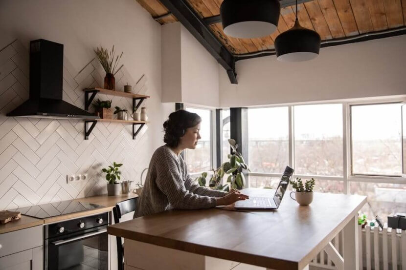 Person studying German personal pronouns on a laptop in a bright and modern kitchen setting.