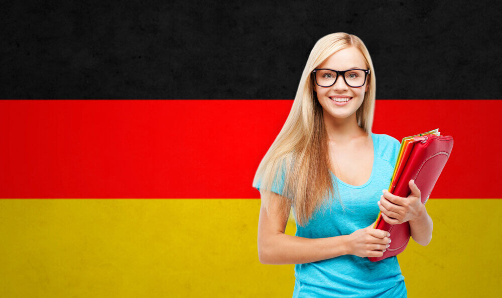 Smiling student holding folders in front of a German flag representing the German Nominative Case.