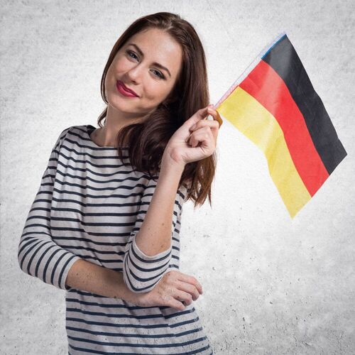 Smiling woman holding a German flag, representing enthusiasm for learning German grammar and forming German questions