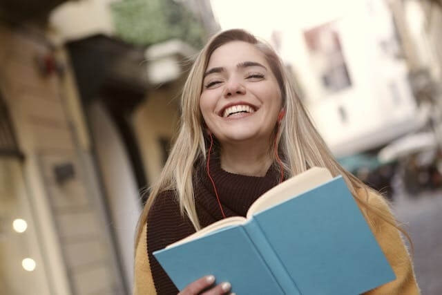 Smiling woman reading a book to practice German cases through a quiz.