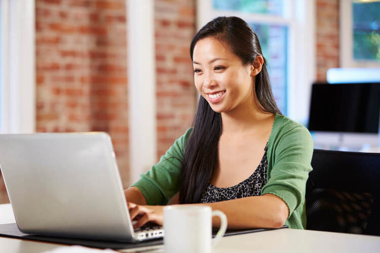 Smiling woman studying German Cases on a laptop in a bright office space