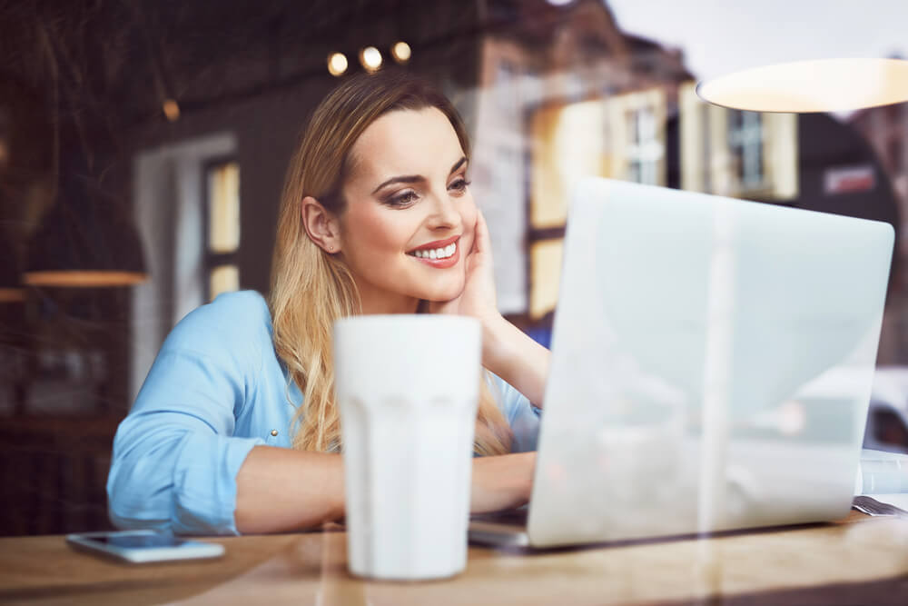 Smiling woman using a laptop to show engagement with a German cases grammar quiz online