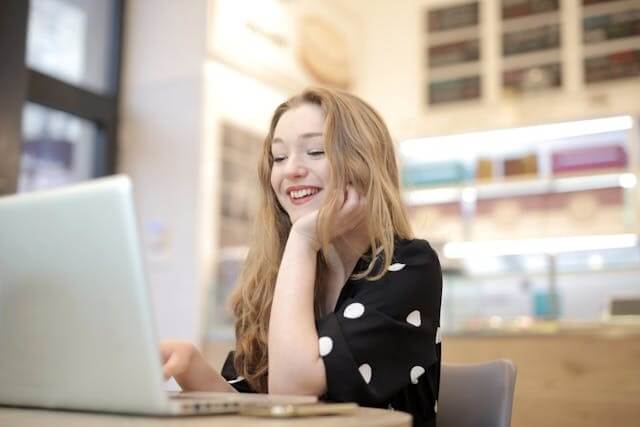 Smiling woman using a laptop to symbolize learning with the German N-Deklinion (N-Declension) quiz