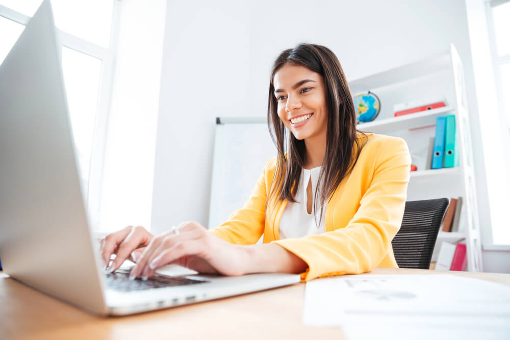 Smiling woman working on a laptop to show engagement with the German two-way prepositions quiz.