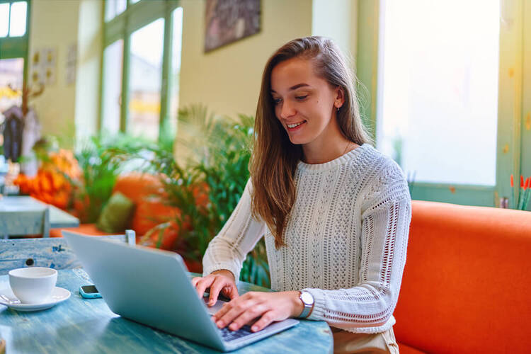 Smiling woman working on a laptop to show focus on our German past perfect tense grammar quiz.