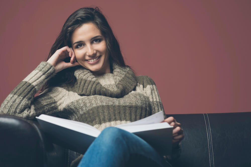 Student sitting on a couch reading a book about German Passive voice.