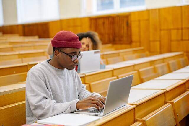 Student studying German consecutive clauses on a laptop in a lecture hall.