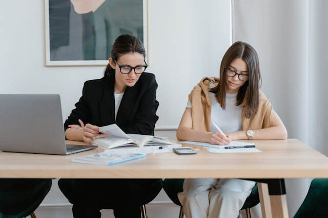 Two students studying together at a desk, learning the German Nominative Case.