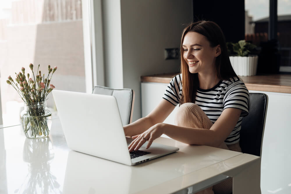 Woman learning German modal verbs online with a laptop in a cozy setting.