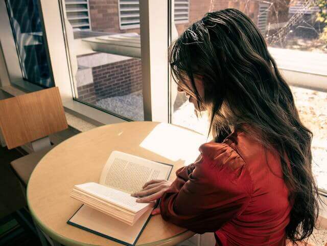 Woman reading a book to study German Future 2 Tense grammar structure