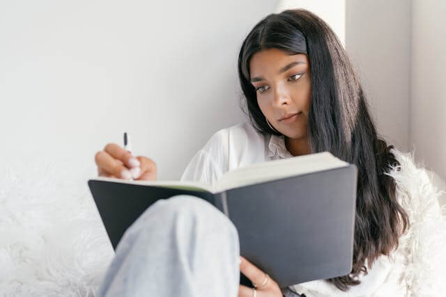 Woman studying German dative verbs while writing in a notebook.