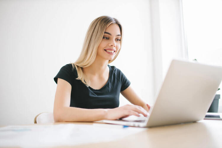 Woman studying German modal verbs on her laptop in a bright room.