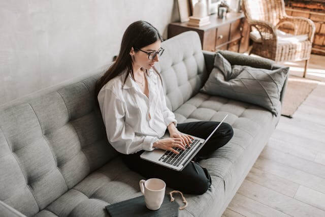 Woman studying German two-way prepositions on a laptop in a cozy living room.