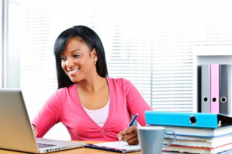 Woman studying online, writing notes to understand German Causal Clauses.