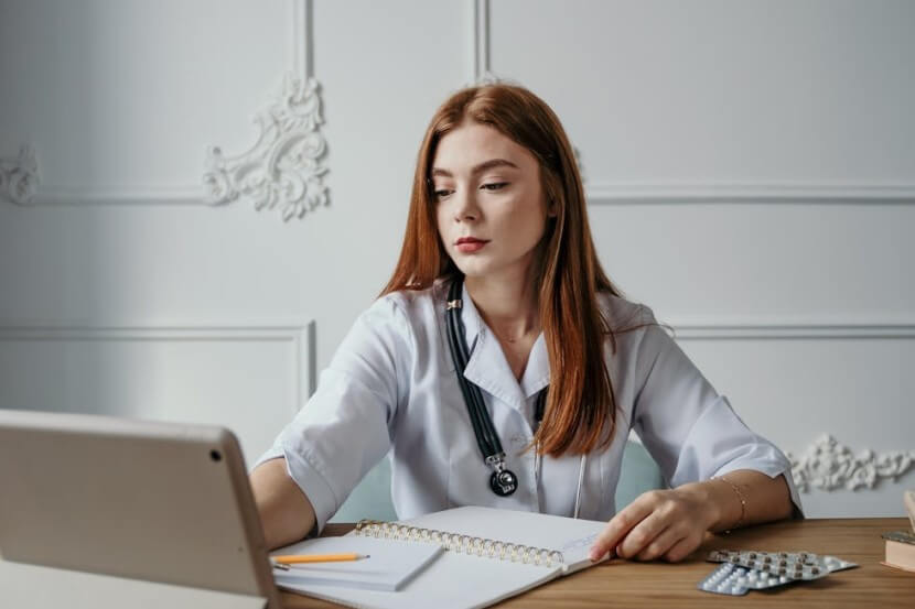 Female doctor working at a desk with a stethoscope, representing German medical vocabulary like die Ärztin (doctor).