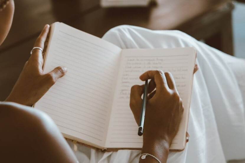 Person writing plans in a notebook, illustrating German vocabulary for plans and wishes, including der Wunsch (wish) and der Plan (plan).